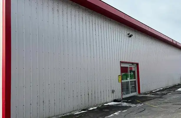 warehouse metal siding with mold, dirt and grass