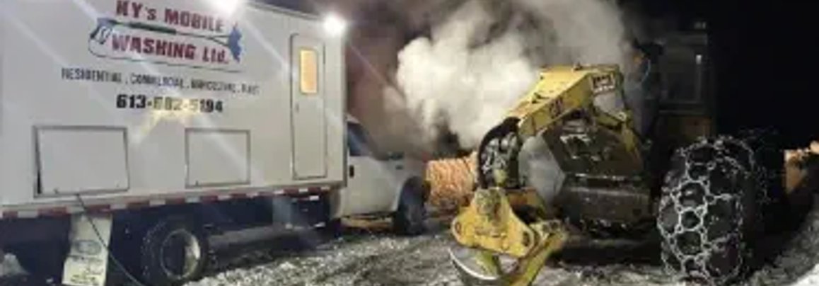 A picture of a man pressure washing heavy equipment