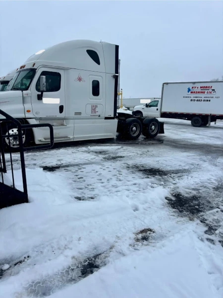 A picture of a man pressure washing a transport truck